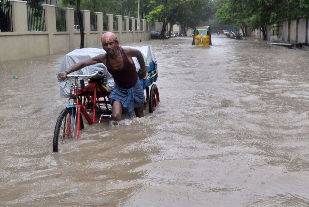 Un trabajador indio empuja su motocicleta a travs de una calle...