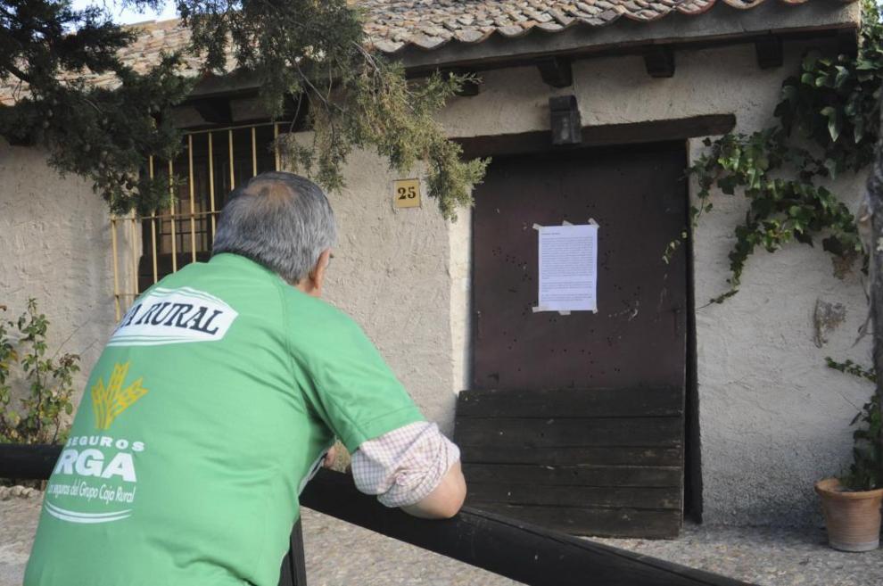 Un hombre lee un cartel colocado en la casa de Basardilla (Segovia)...