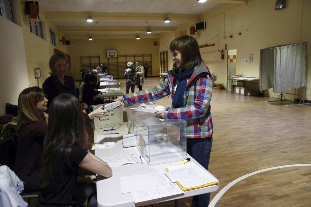 Una funcionaria entrega en una mesa electoral los votos por correo que...
