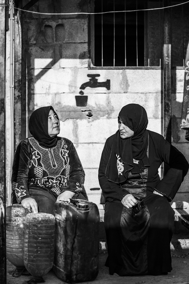Dos mujeres charlan en la zona de recogida de agua en el asentamiento...