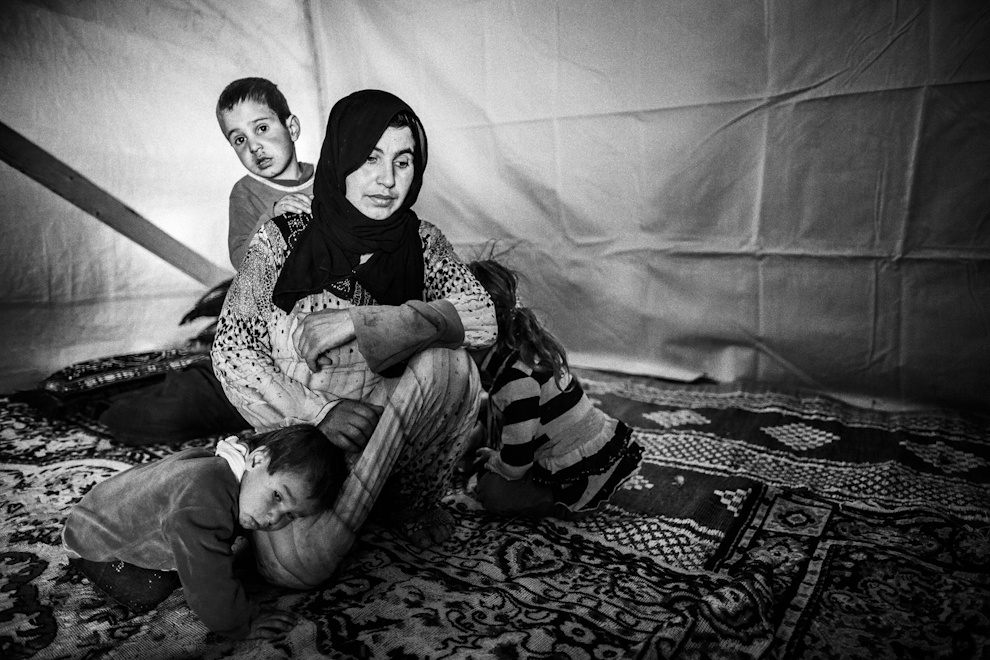 Una madre con sus hijos dentro de su tienda del campo de refugiados de...