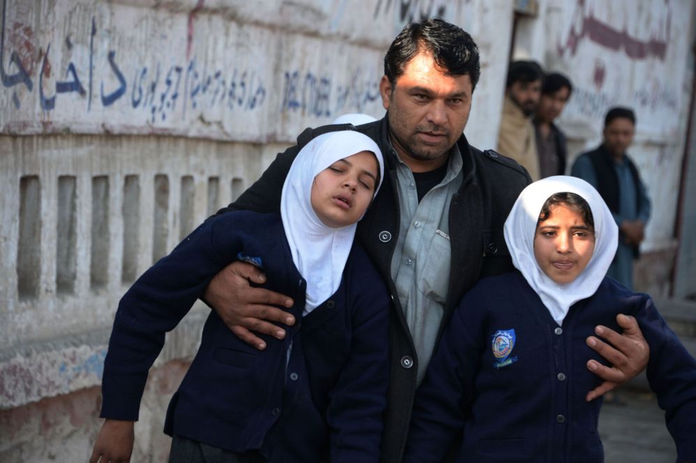 Un hombre afgano asiste a dos jovenes en las proximidades de un ataque...