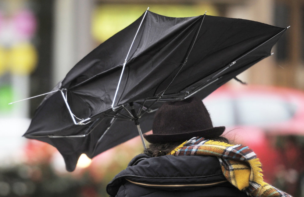 Una mujer se protege en Pamplona de la lluvia y el viento con su...