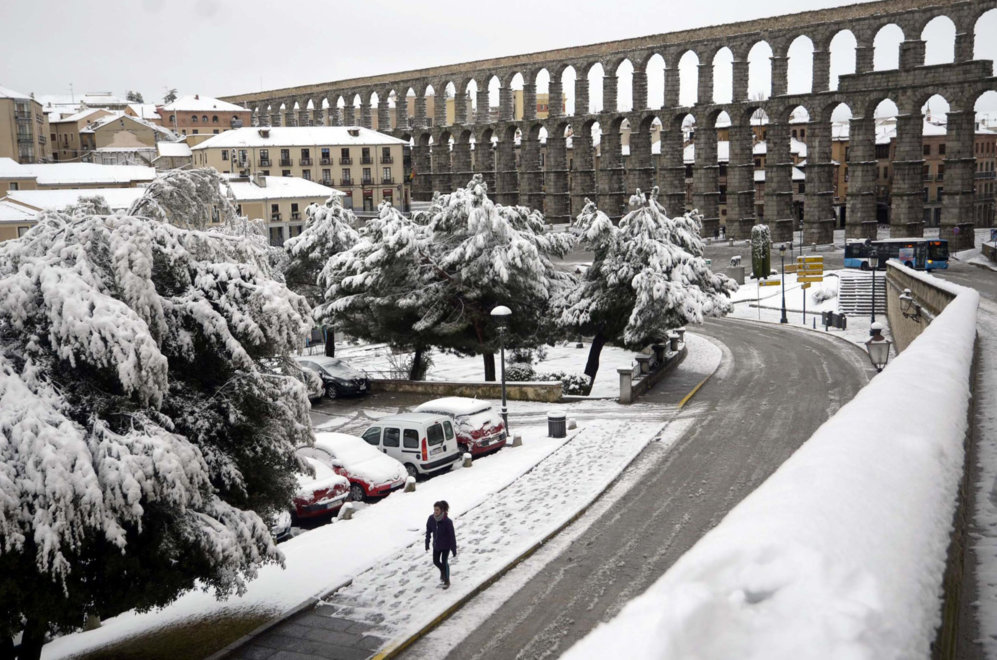 Una mujer camina por una calle junto al Acueducto de Segovia, que...