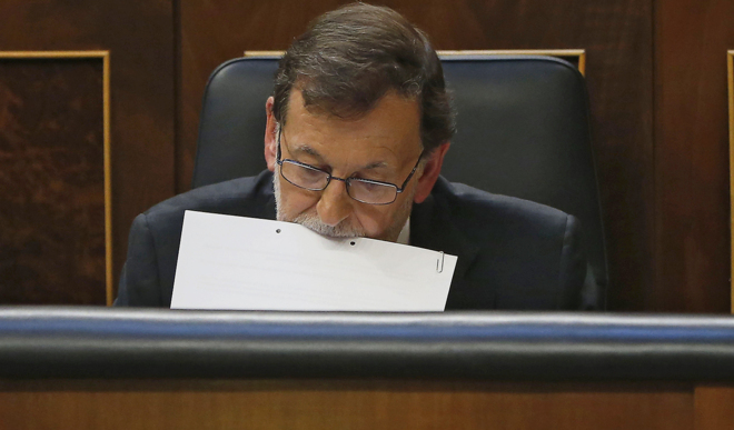 Mariano Rajoy sujeta unos papeles con la boca durante el pleno del...