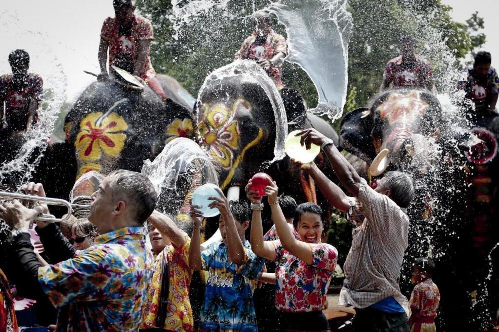 Varios elefantes mojan a un grupo de asistentes durante la...