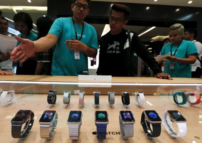 Clientes en una tienda observando los Smart Watch de Apple, en...
