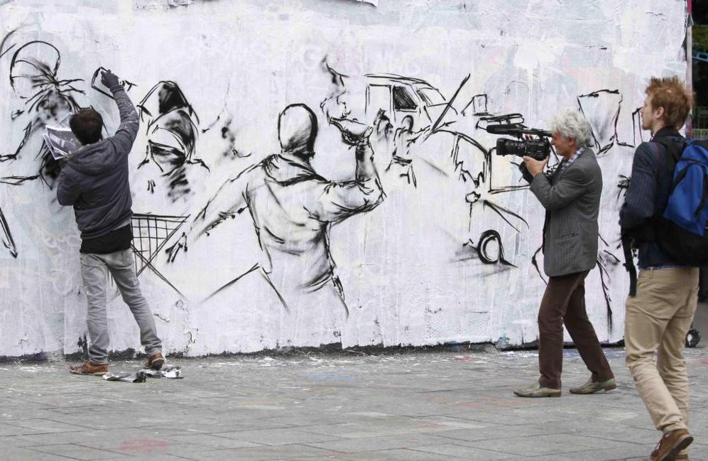 Un artista callejero pinta un mural en Pars durante una...
