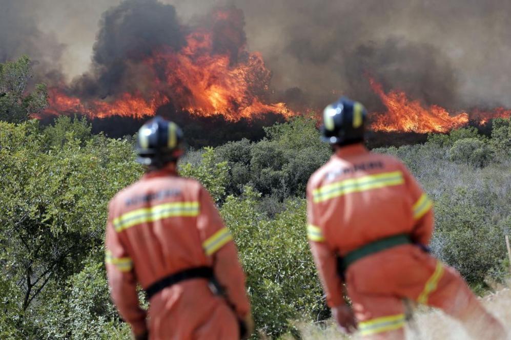 Dos bomberos observan las llamas cerca de la localidad de Sumacrcel...