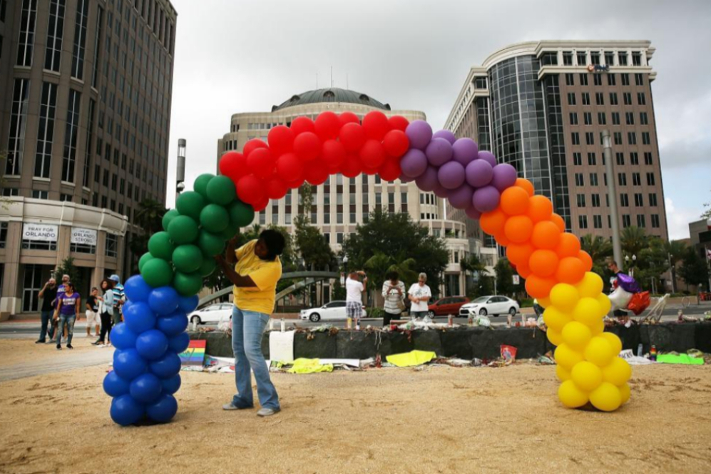 Una mujer construye un arcoiris con los colores de la bandera LGTB en...