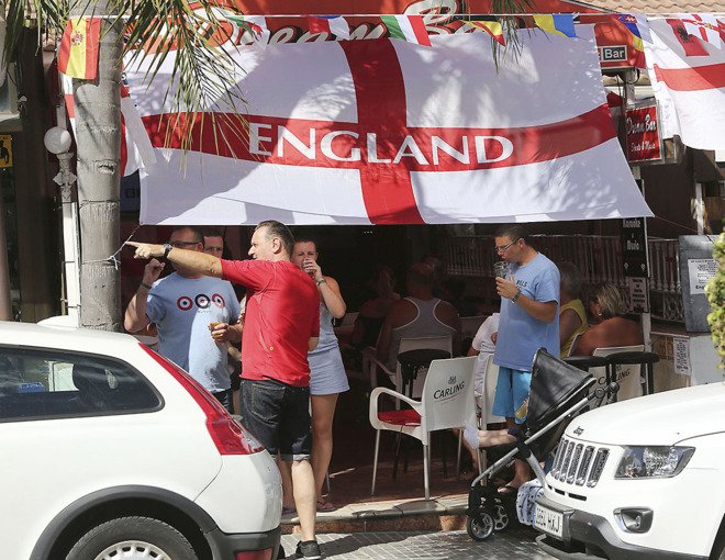 Un grupo de ingleses bebe en una terraza con la bandera de su pas,...