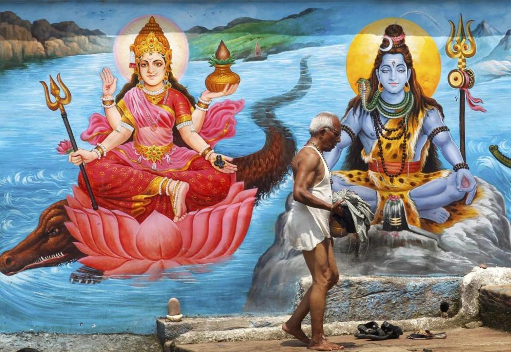 Un hind pasando por delante del mural de las deidades hindes en la...