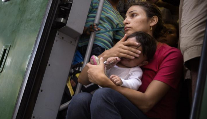 Una refugiada tapa la cara a su hijo en la estacin de Keleti...
