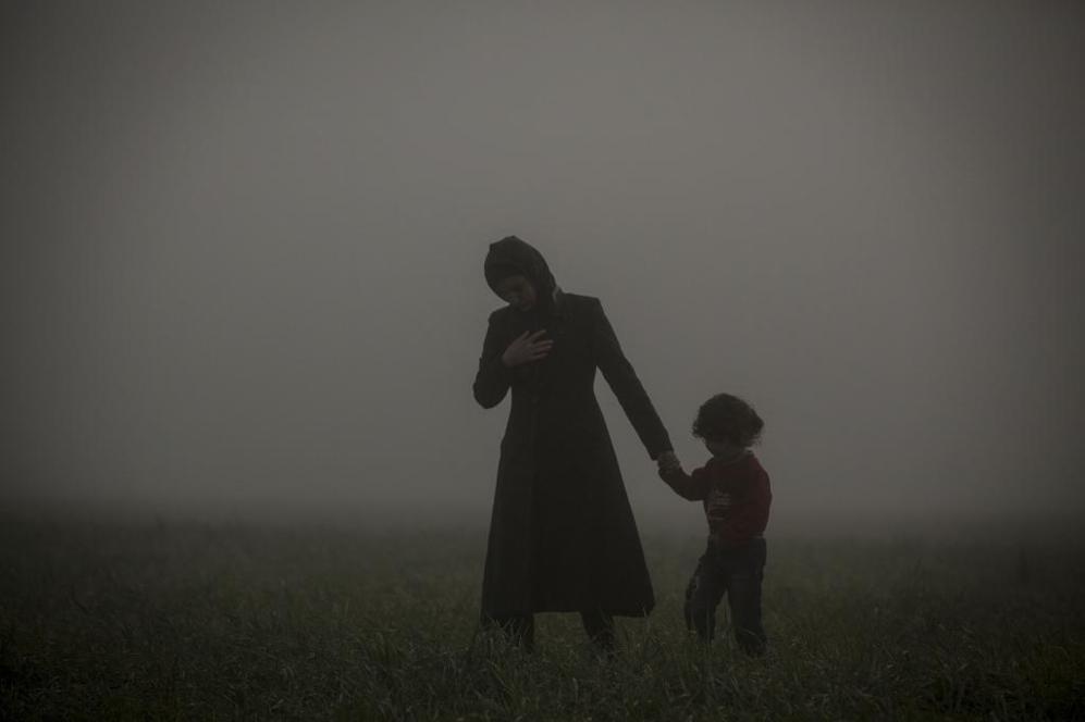 Una madre y su hija caminando en los alrededores del campo improvisado...