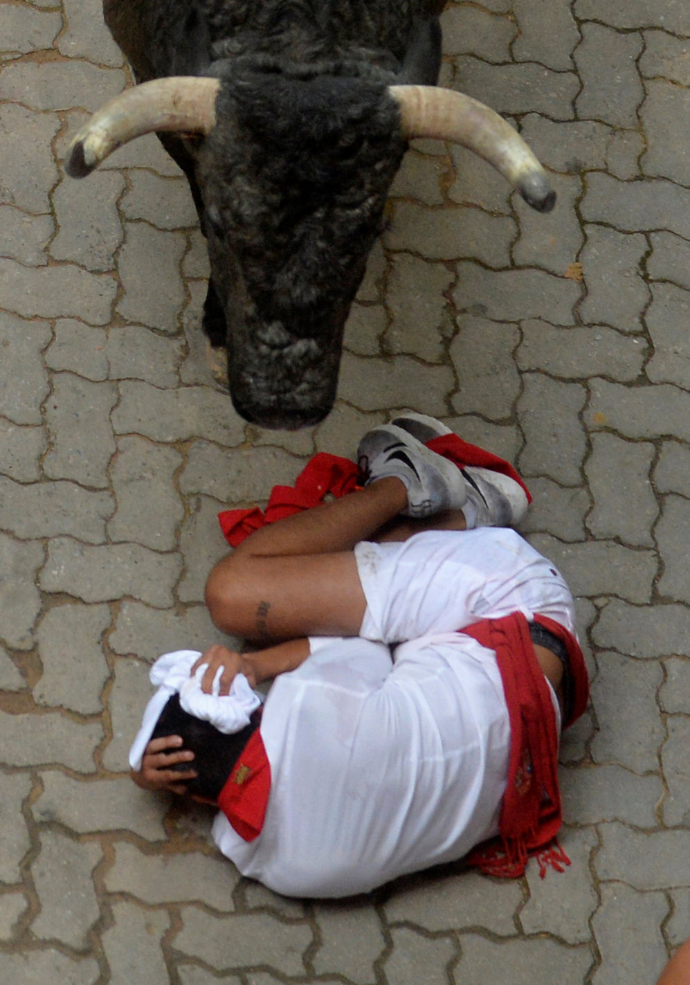 Un corredor cae delante de un toro cerca de la entrada a la plaza de...