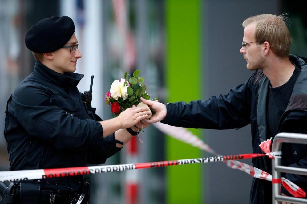 Un peatón entrega un ramo de flores a un policía para que los...