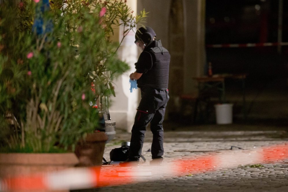 Un polica manipula un objeto sospechoso en el lugar de atentado