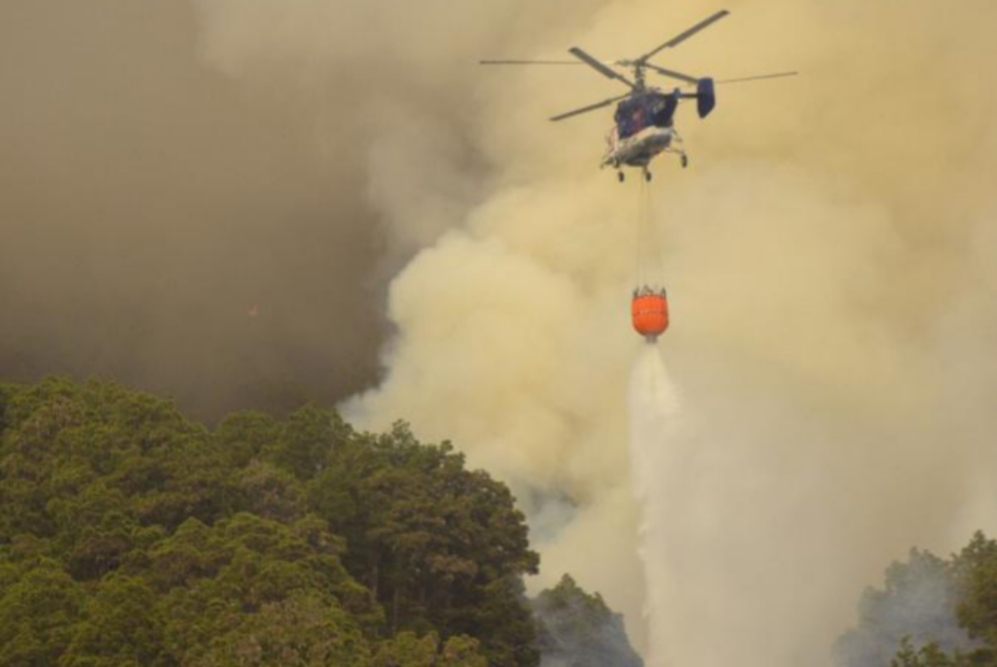 Un helicptero descarga agua sobre el fuego que comenz ayer en el...