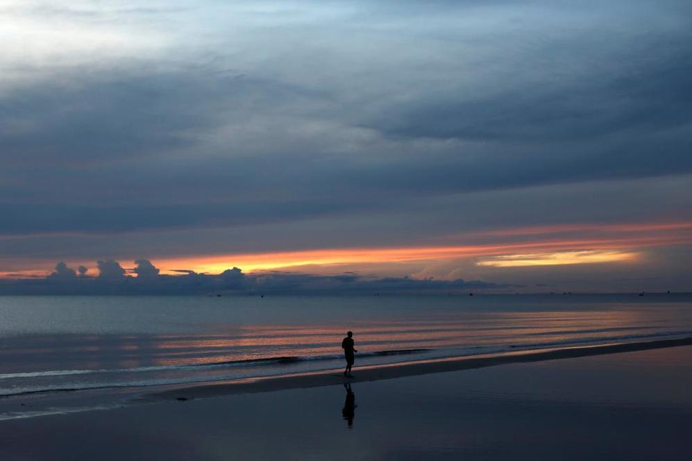 Un hombre pasea por la orilla de una de las playas en Hua Hin,...