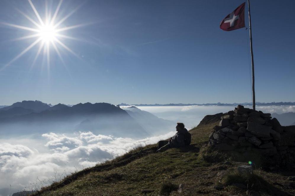 Un alpinista descansa en lo alto del pico Alvier en Suiza.