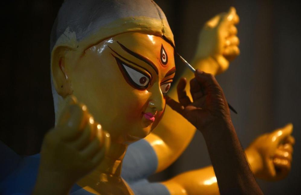 Un artesano indio trabaja esculturas de barro inspiradas en dolos...