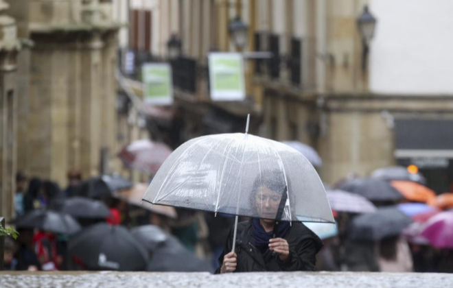 Una mujer se cubre con un paraguas en una maana lluviosa