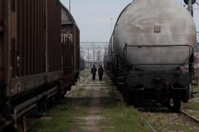 Dos inmigrantes caminan entre trenes abandonados en Tesalnica.