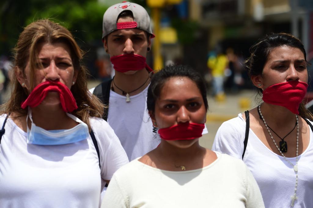 Gagged with red clothes, opposition activists march towards the Catholic Church's episcopal seats nationwide, in Caracas, on April 22, 2017. Venezuelans gathered Saturday for "silent marches" against President Nicolas Maduro, a test of his government's tolerance for peaceful protests after three weeks of violent unrest that has left 20 people dead. / AFP PHOTO / RONALDO SCHEMIDT