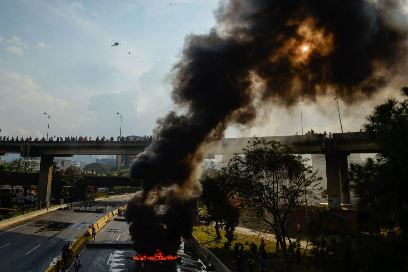 Opositores venezolanos prenden fuego a las barricadas durante la...