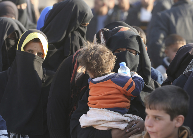 Una mujer y su bebé esperan para recibir ayuda humanitaria tras salir...