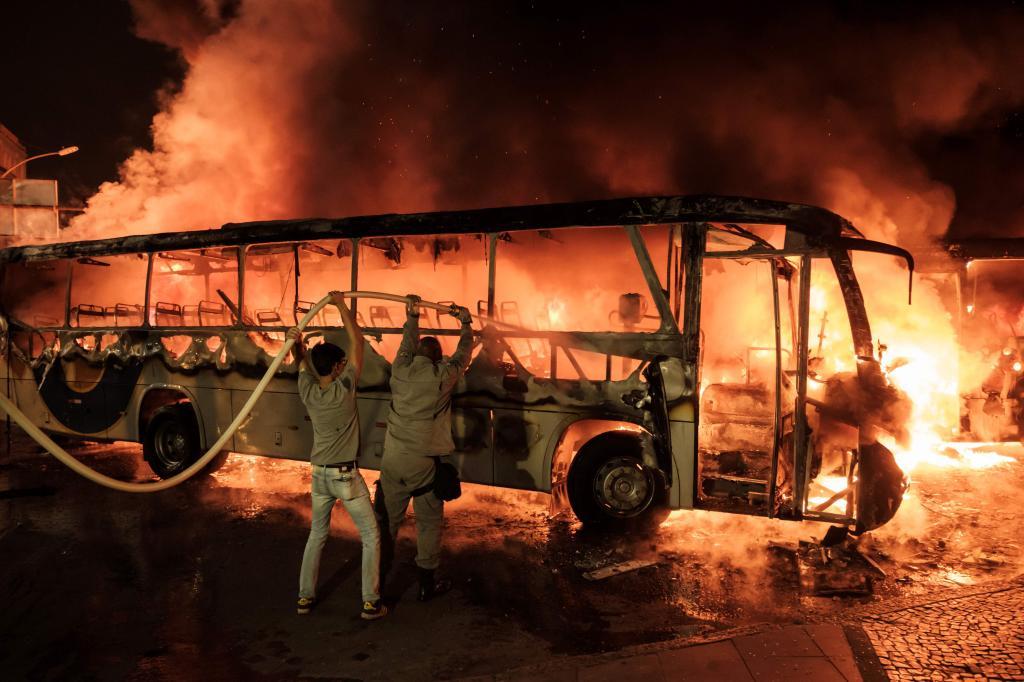 Bomberos intentan sofocar las llamas de un autobs incendiado en Ro de Janeiro durante la huelga general en Brasil.