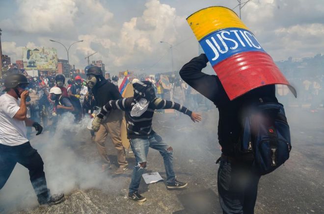 Un manifestante se cubre con un escudo casero durante los disturbios del mircoles en Caracas.