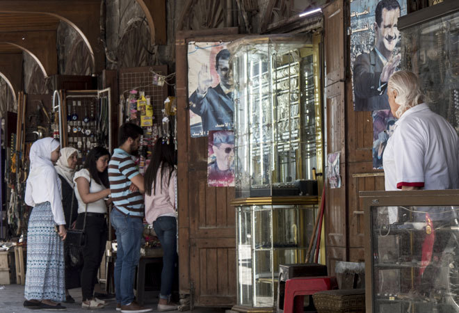Un grupo de sirios busca entre tiendas con carteles de Bashar Asad.