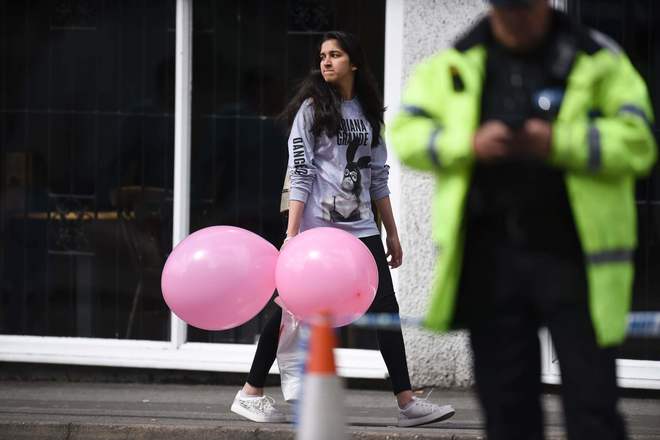 Una joven, con varios globos del concierto, ante un agente.