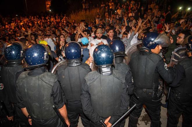 Centenares de personas a una unidad antidisturbios de polica, durante las manifestaciones de la noche del mircoles, en Alhucemas.