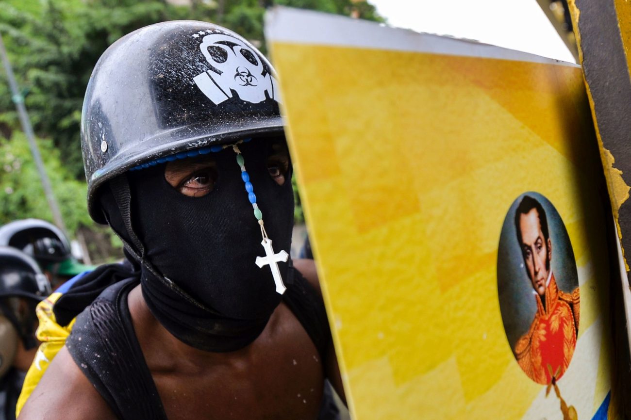 Un activista de la oposicin se esconde detrs de un escudo durante...