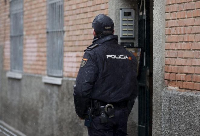 Un agente de la Polica Nacional custodia la entrada a una vivienda.