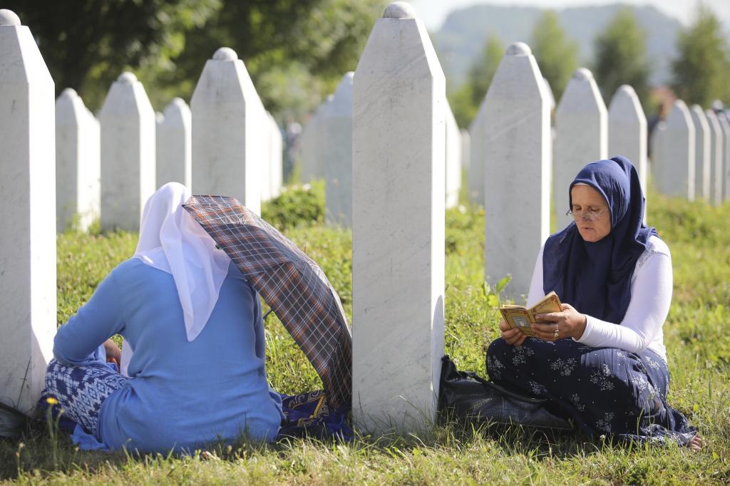 Dos mujeres se sientan junto a la tumba de un familiar en el Centro memorial de Srebrenica (Bosnia-Herzegovina)