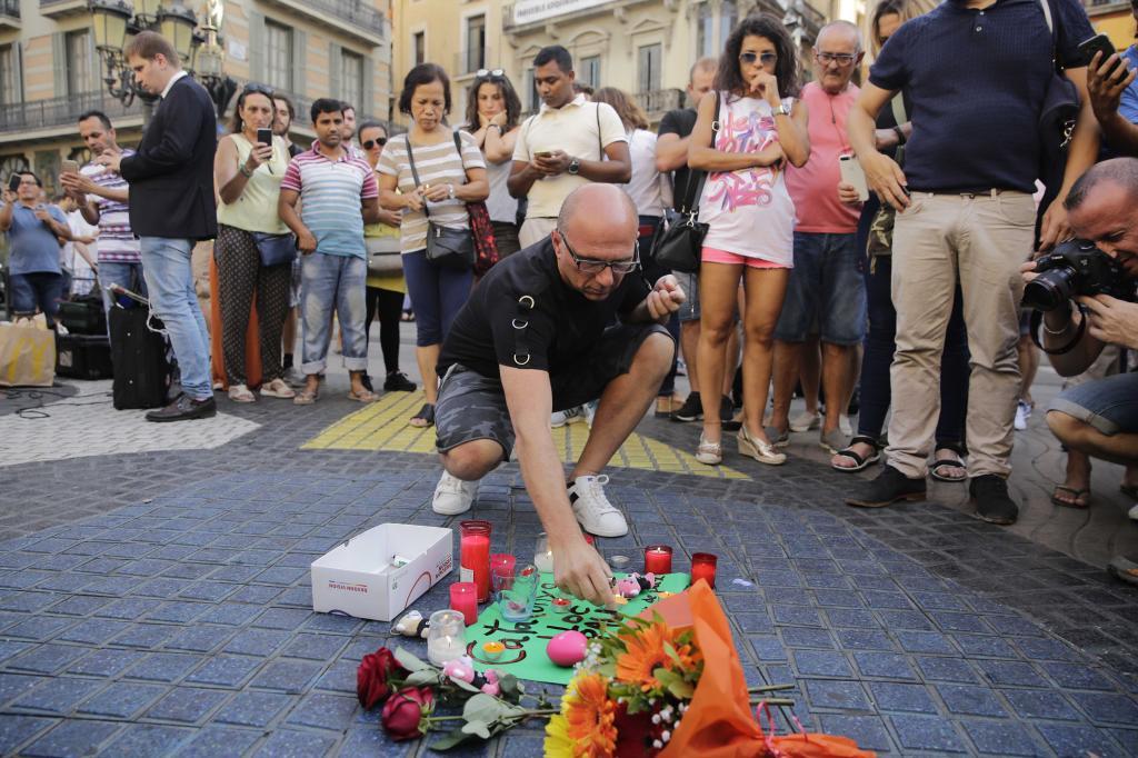 En las calles de Barcelona, algunas personas colocan flores, velas y...