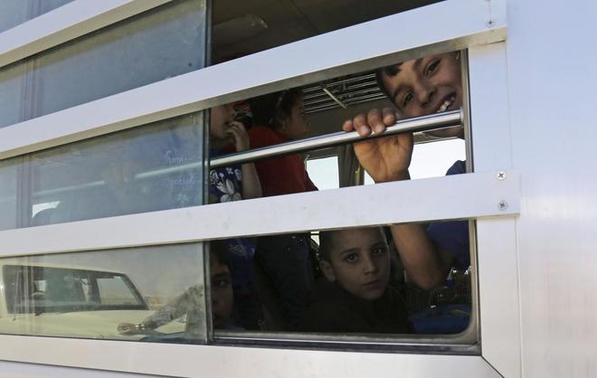 Nios de milicianos del Estado Islmico miran por la ventana al paso del convoy que ha sido bloqueado.