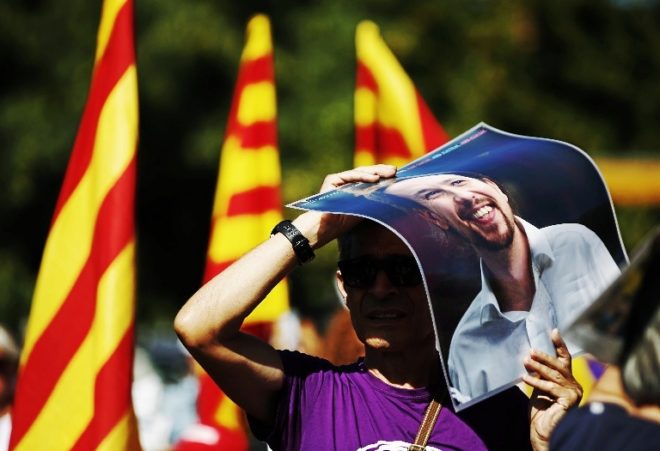 Un hombre se tapa del sol con una imagen de Pablo Iglesias, ayer en la...