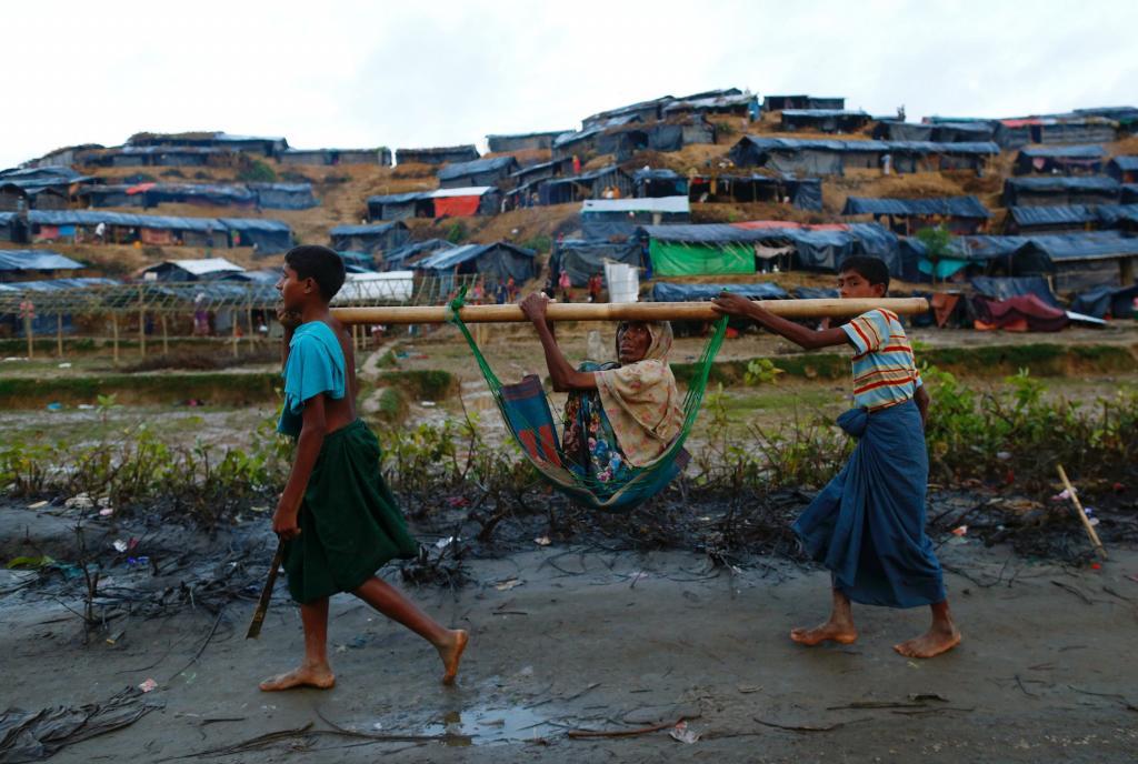 Dos nios rohingya llevan a una anciana por el campamento de...
