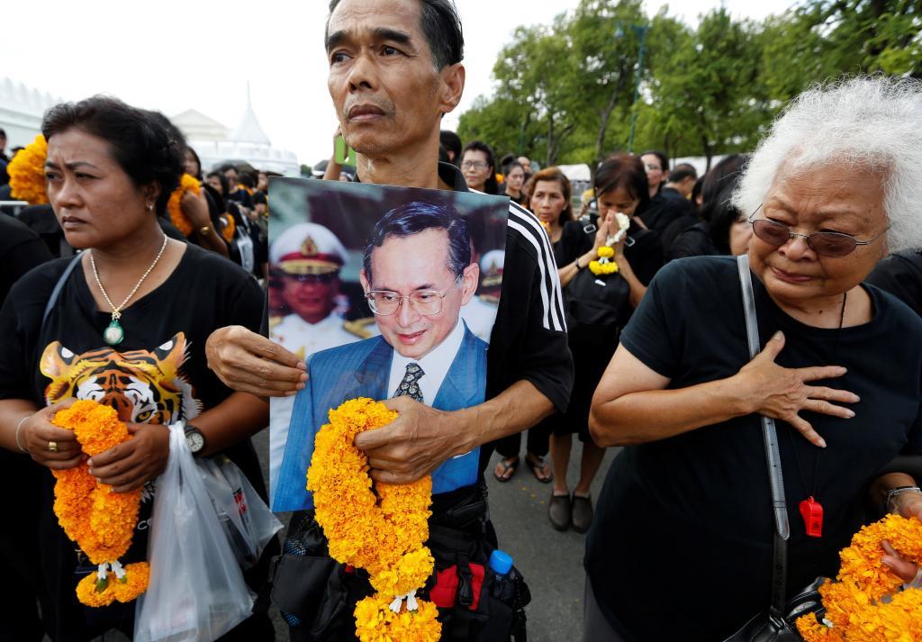 Un ciudadano lleva un retrato del fallecido rey Bhumibol Adulyadej de Tailandia mientras aguarda para poder presentarle sus respetos a las puertas del Gran Palacio en Bangkok (Tailandia).