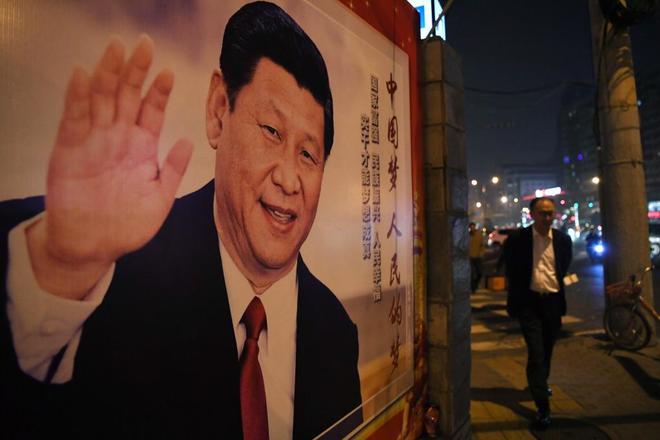 Un hombre camina junto a un retrato de Xi Jinping en Pekín.