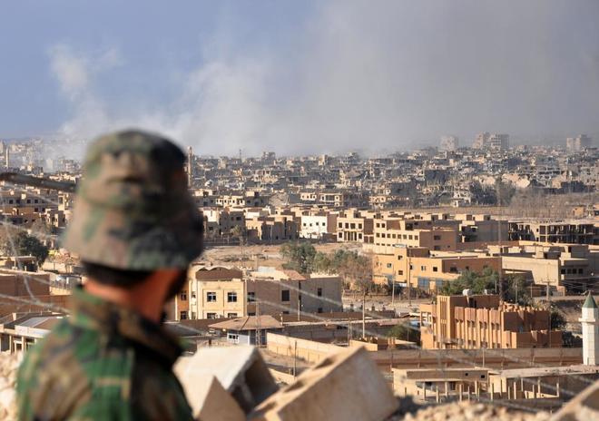 Un miembro de las fuerzas gubernamentales sirias observa la ciudad de Deir Ezzor tras un ataque areo.