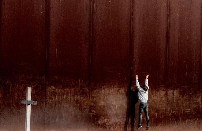 Un hombre salta frente a la pared de metal en el Memorial del Muro de Berln.