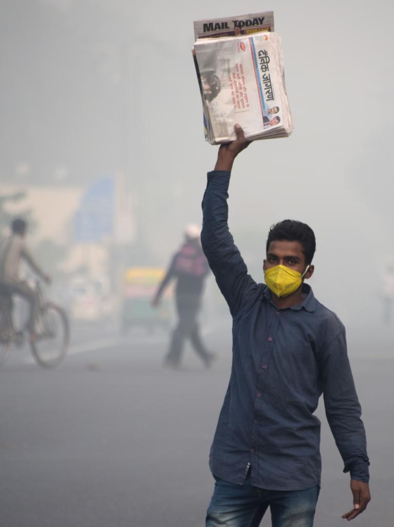 Un vendedor de peridicos indio trabaja en una calle de Nueva Delhi envuelta en polucin.