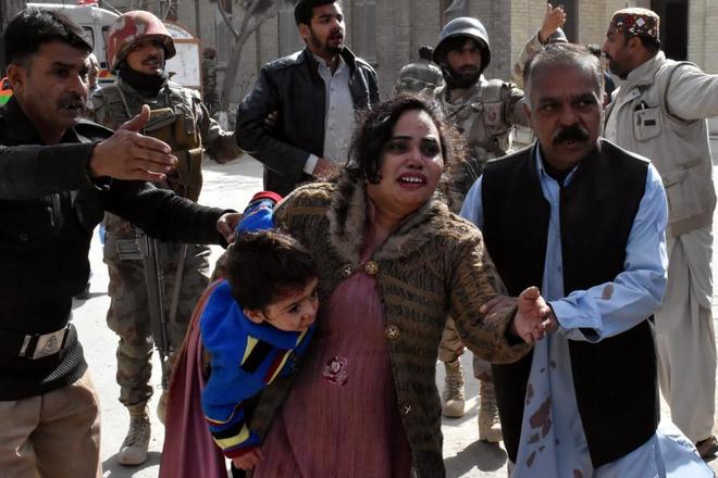 Una mujer huye de la iglesia paquistan con su hijo ensangrentado en brazos.