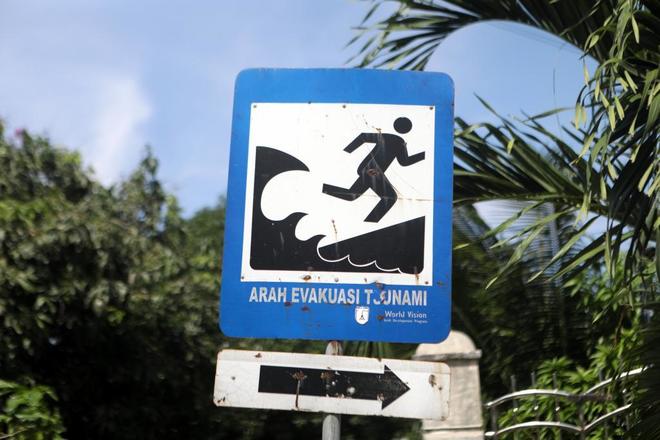 Un viejo cartel con la ruta de evacuacin en caso de tsunami colocado en un cruce de carreteras.
