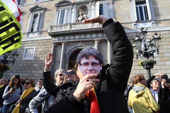 Una mujer, con una careta de Carles Puigdemont ante el Palau de la...
